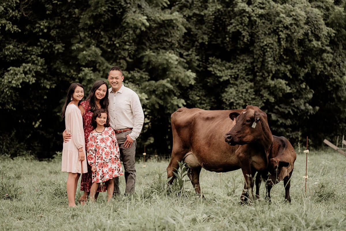 A family in a field next to cows.