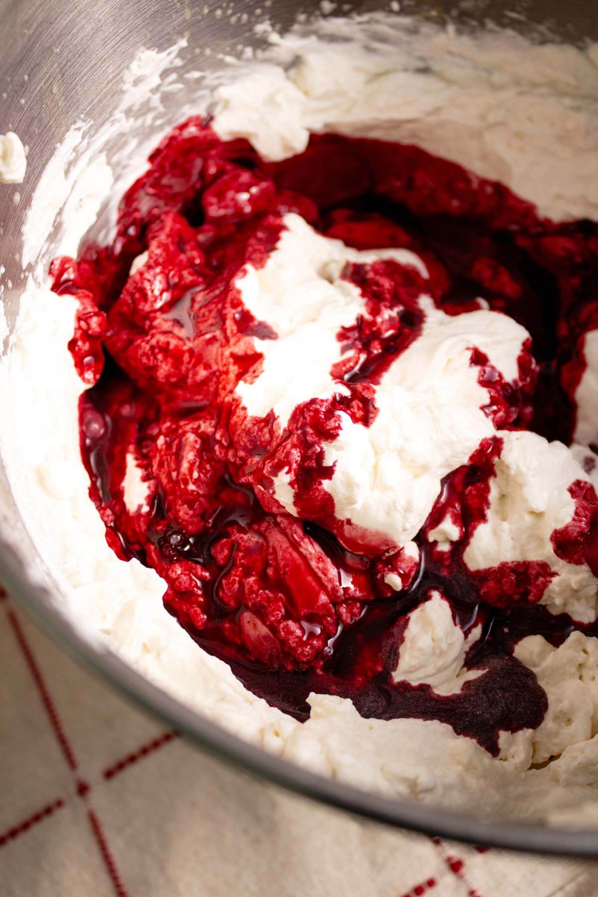 Whipped cream in a bowl swirled with blackberry sauce.
