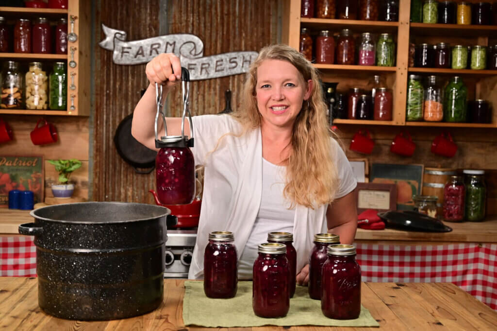 A woman holding up home canned cherries.