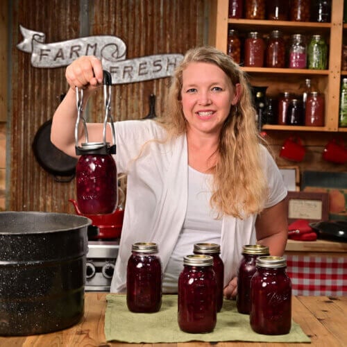 A woman holding up home canned cherries.