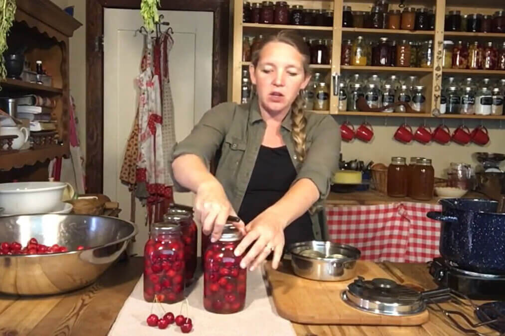 A woman canning cherries in the kitchen.