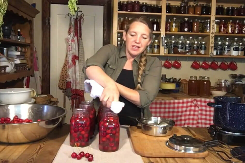 A woman canning cherries in the kitchen.