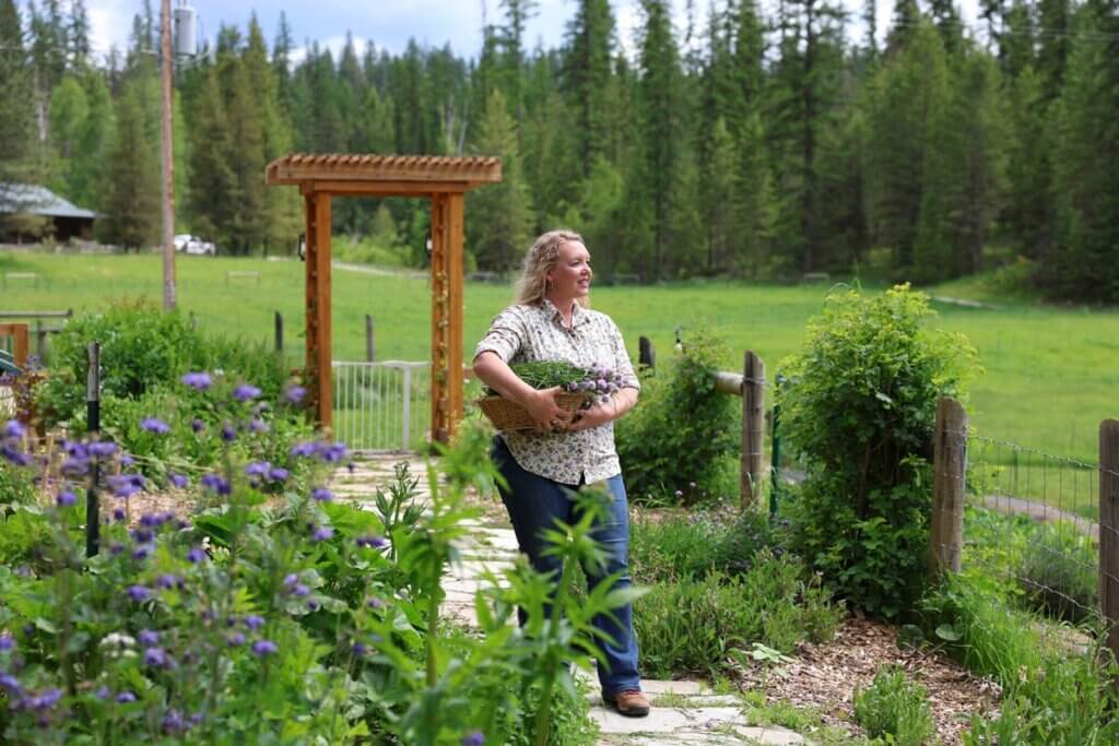 A woman holding a basket of chives in the garden.