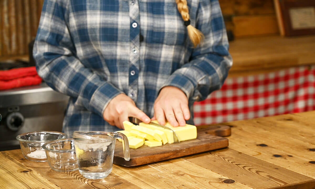 A young woman cutting butter into cubes.