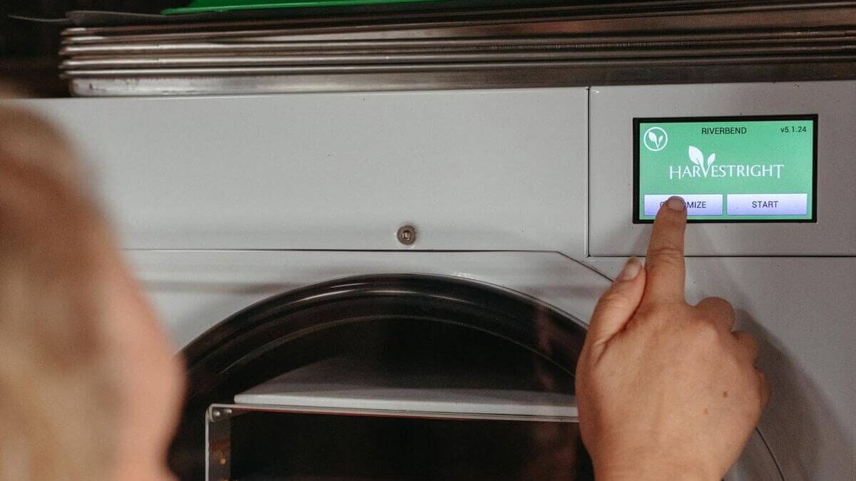 A woman pushing buttons on a freeze dryer.