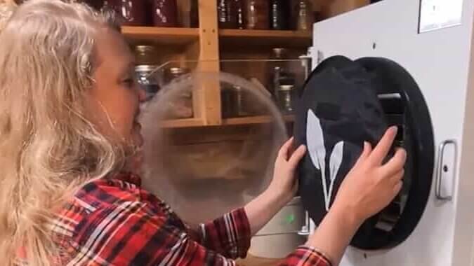 A woman putting the insulation cover onto a Harvest Right freezer dryer.