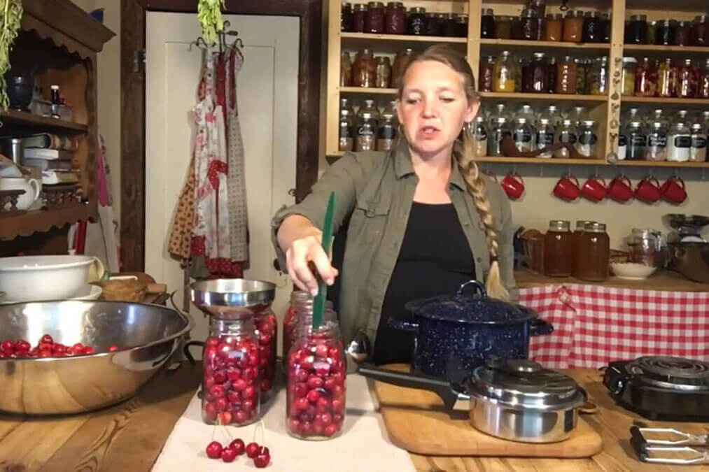 A woman canning cherries in the kitchen.