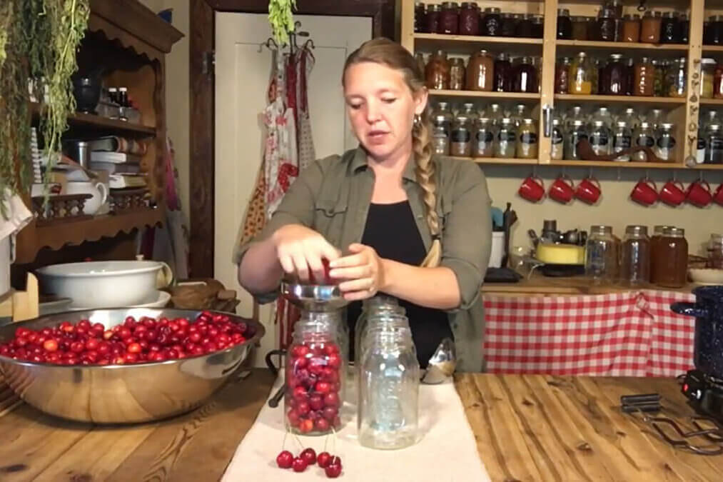 A woman canning cherries in the kitchen.