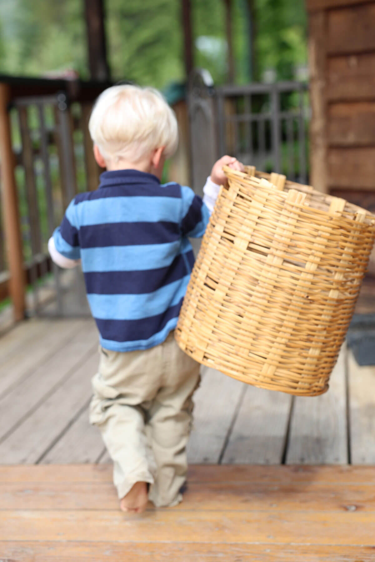A young boy carrying a laundry basket.