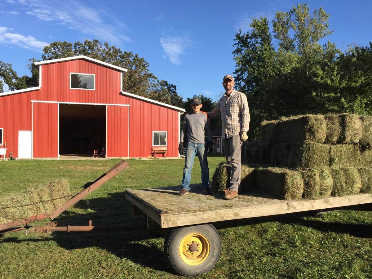 A father and son stacking hay on a trailer.