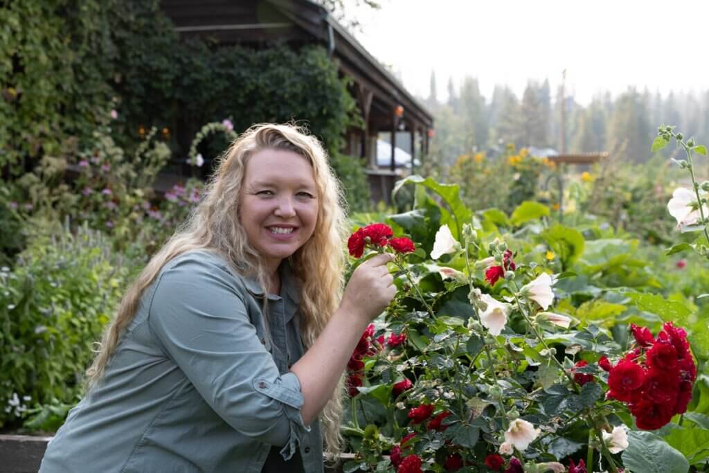 A woman smelling flowers in a garden.