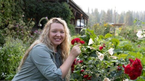 A woman smelling flowers in a garden.