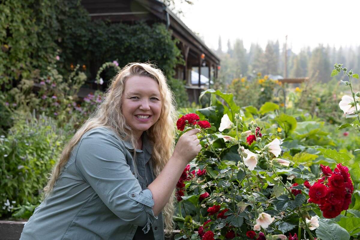 A woman smelling flowers in a garden.