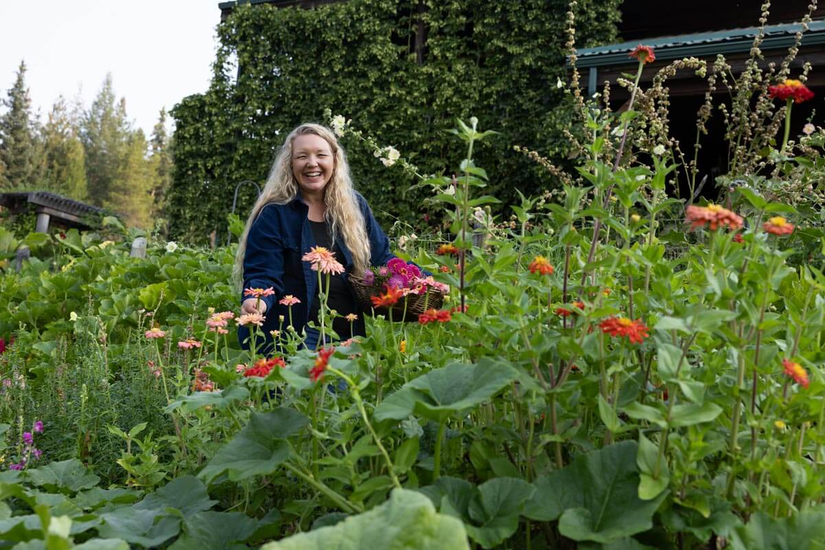 A woman harvesting flowers in a garden.