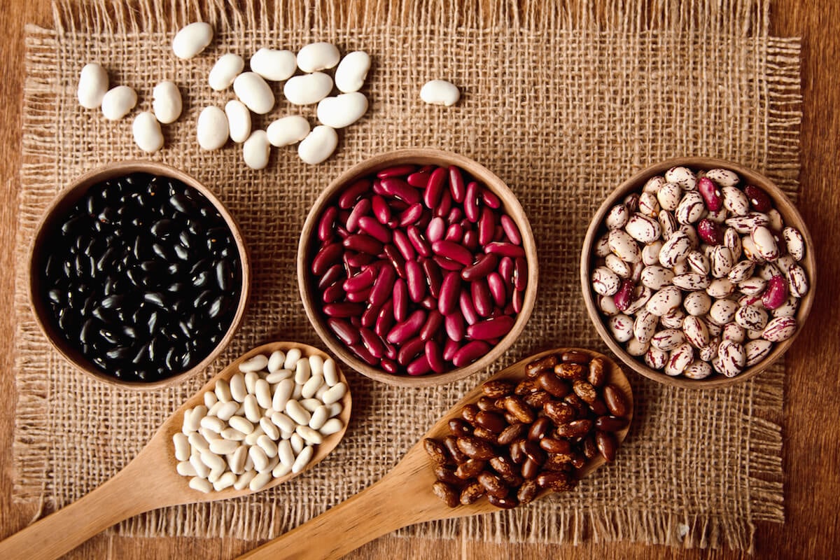 dried beans in bowls and wooden spoons