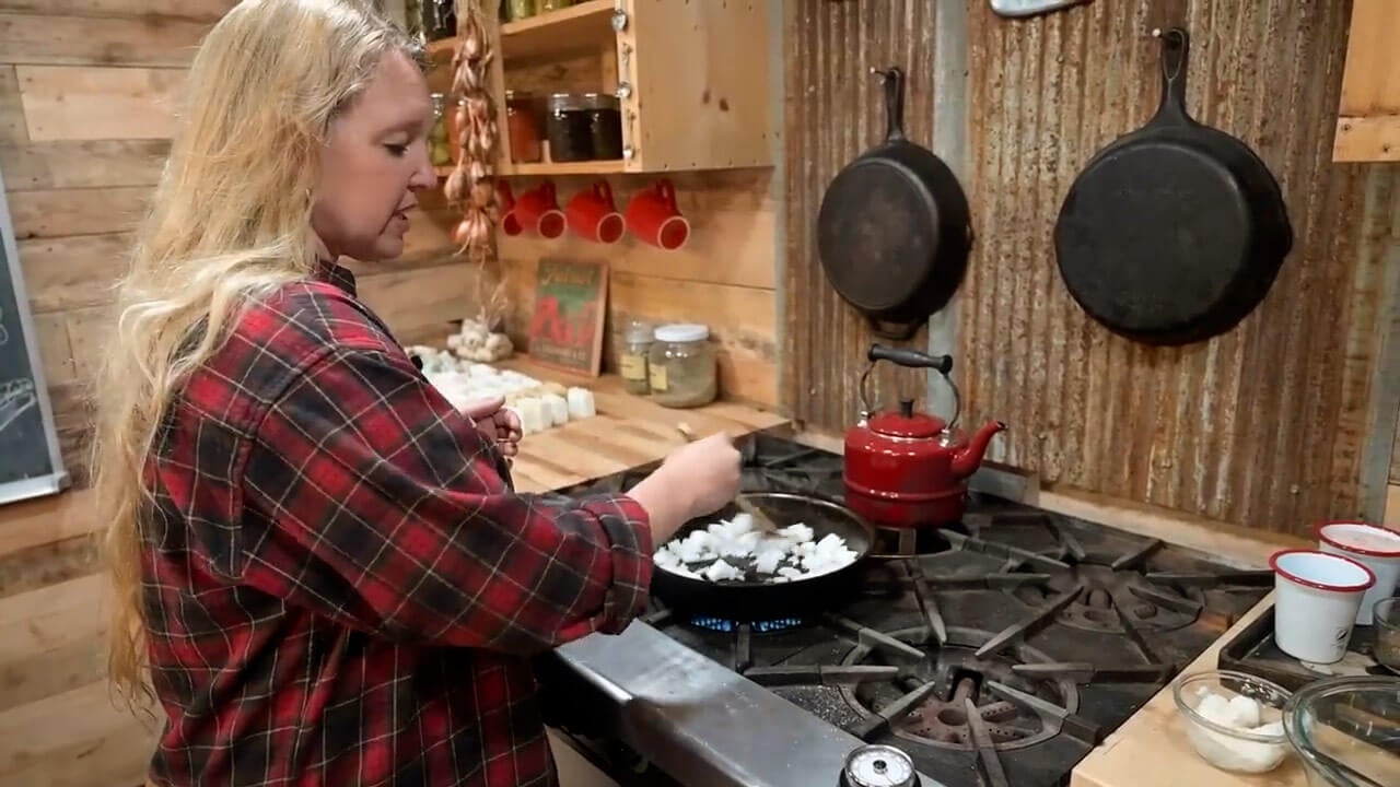 A woman saut&eacute;ing onions in a cast iron pan.