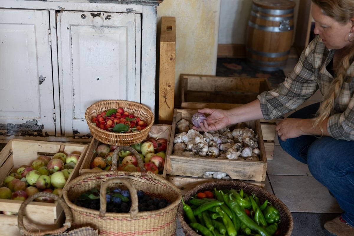 A woman looking at crates of garden harvest.