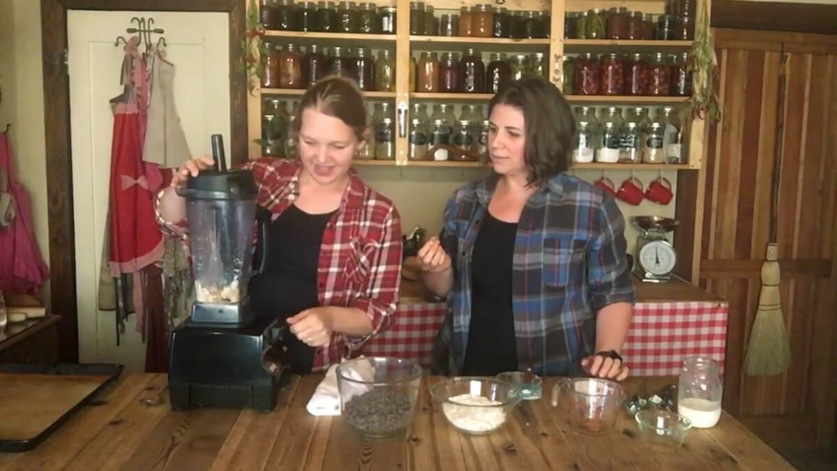 A woman using a high powered blender to make coconut ball filling.