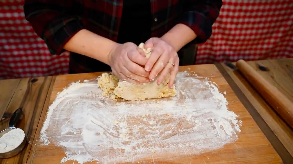 Hands kneading pie crust dough.