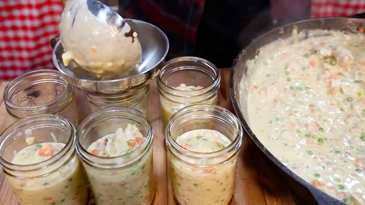 Ladling pot pie filling into glass jars.