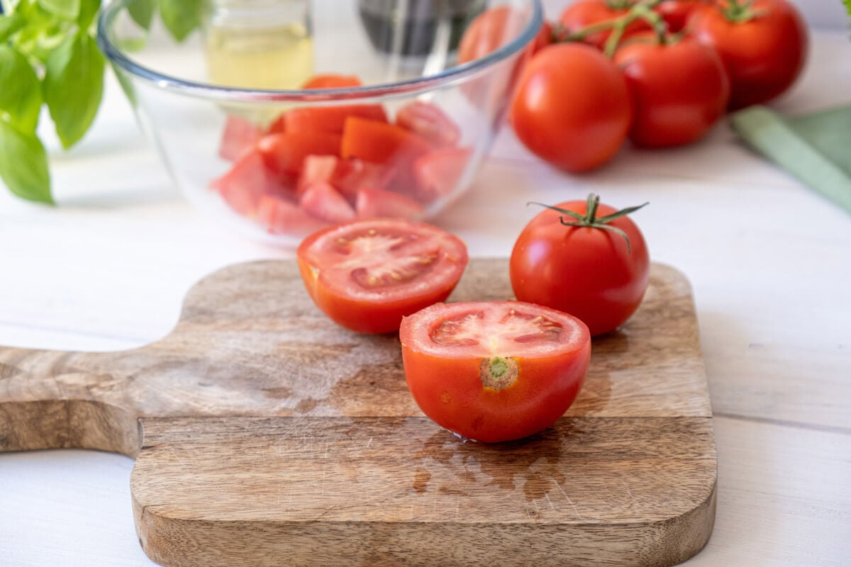 Halved tomatoes on a wooden cutting board.