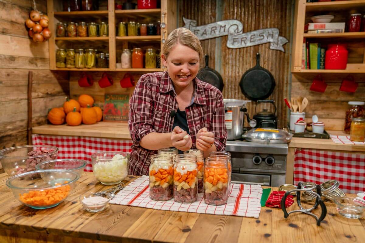 A woman filling jars to can beef stew.