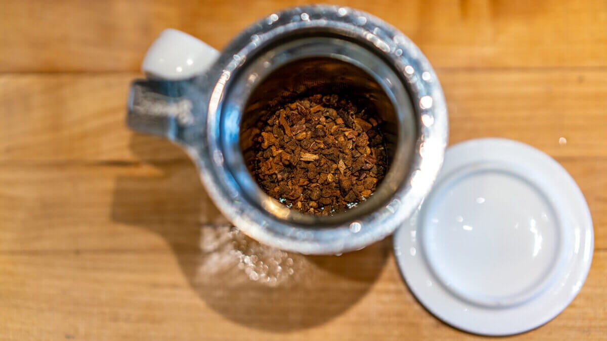 Tea inside a tea steeper in a mug.