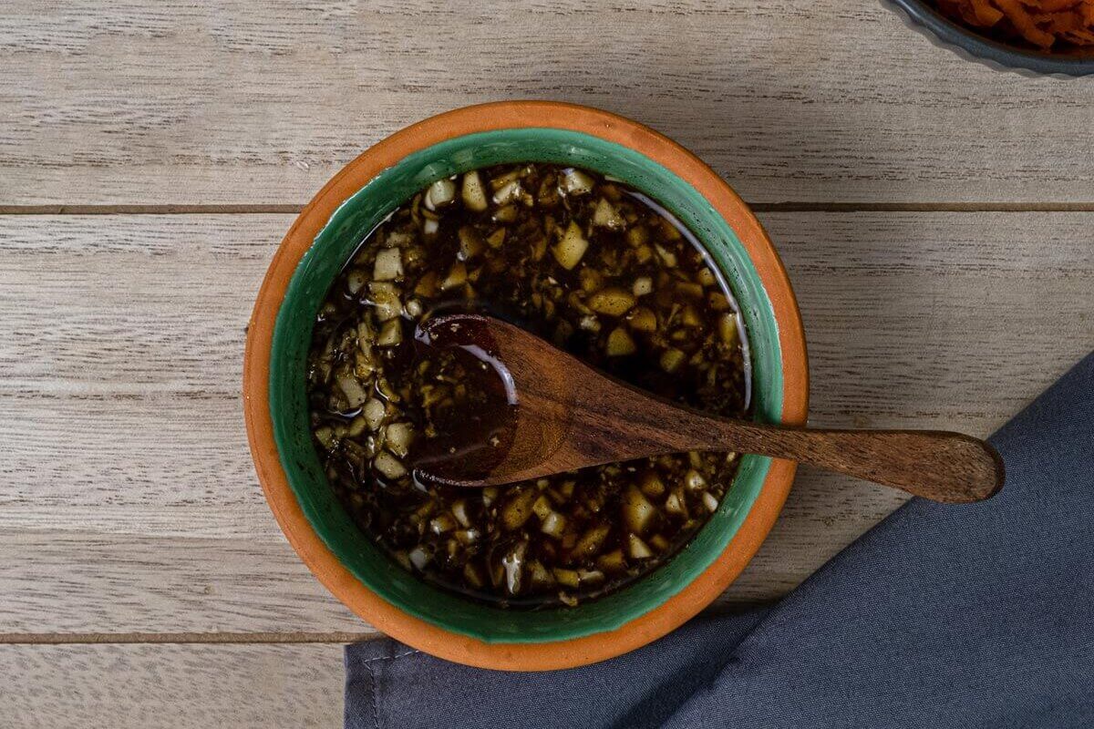 Dressing mixed up in a small bowl with wooden spoon.