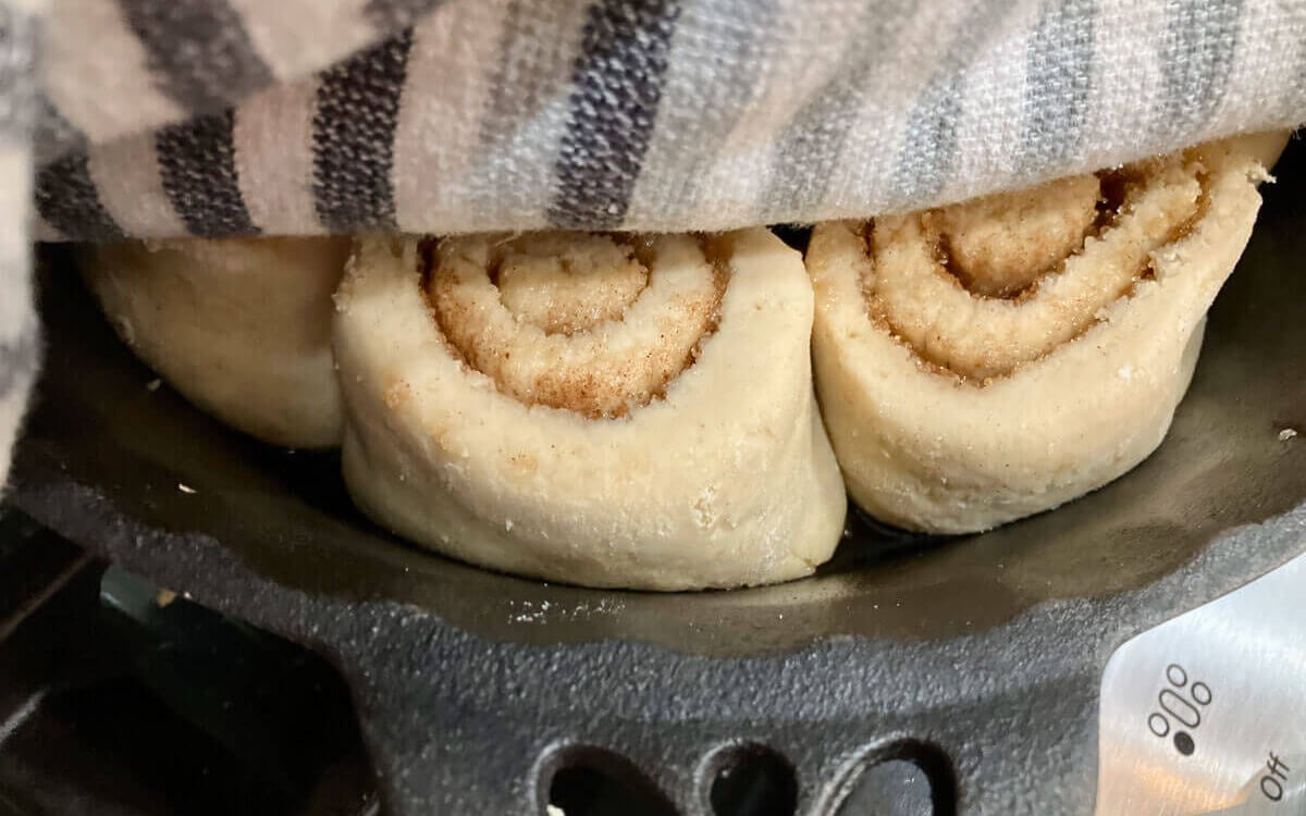 Gluten free cinnamon rolls covered by a tea towel.