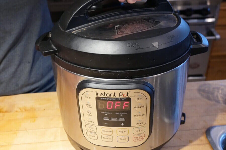 A hand putting the lid onto an Instant Pot.