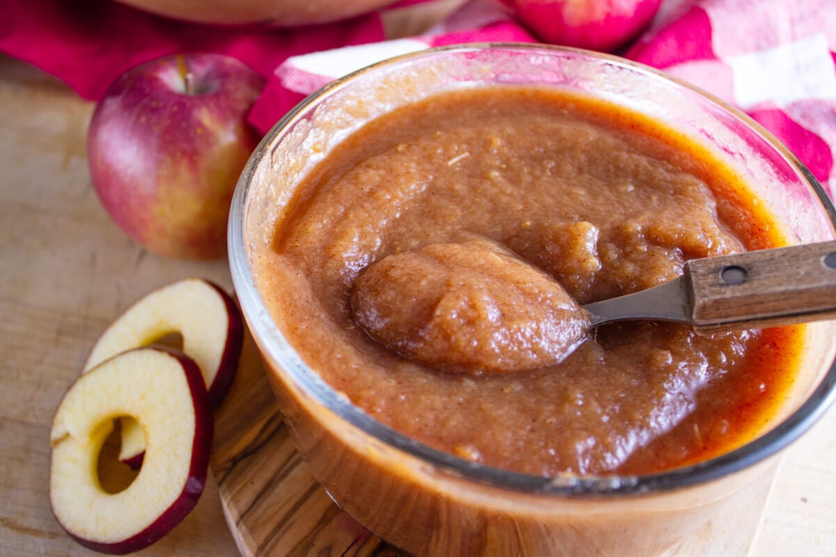 A spoon lifting a bite of applesauce from a bowl.