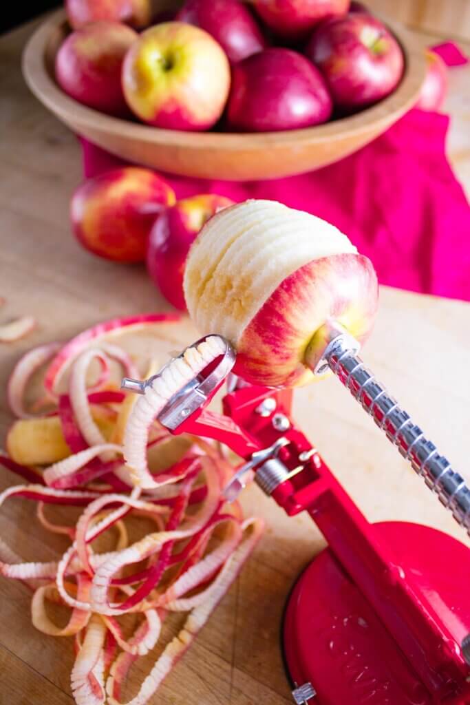 An apple peeler peeling the skin from an apple.