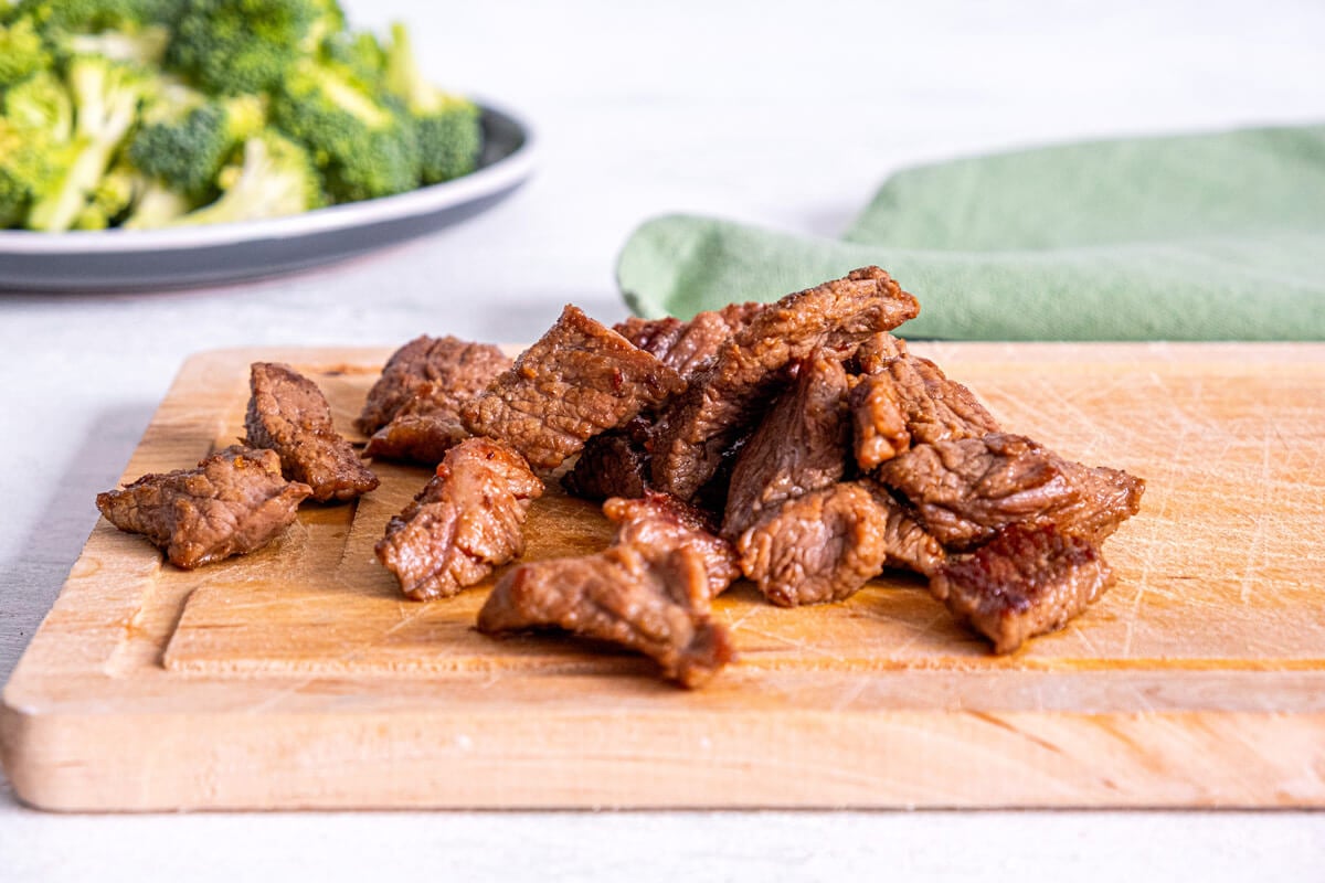 Strips of seared beef on a cutting board.