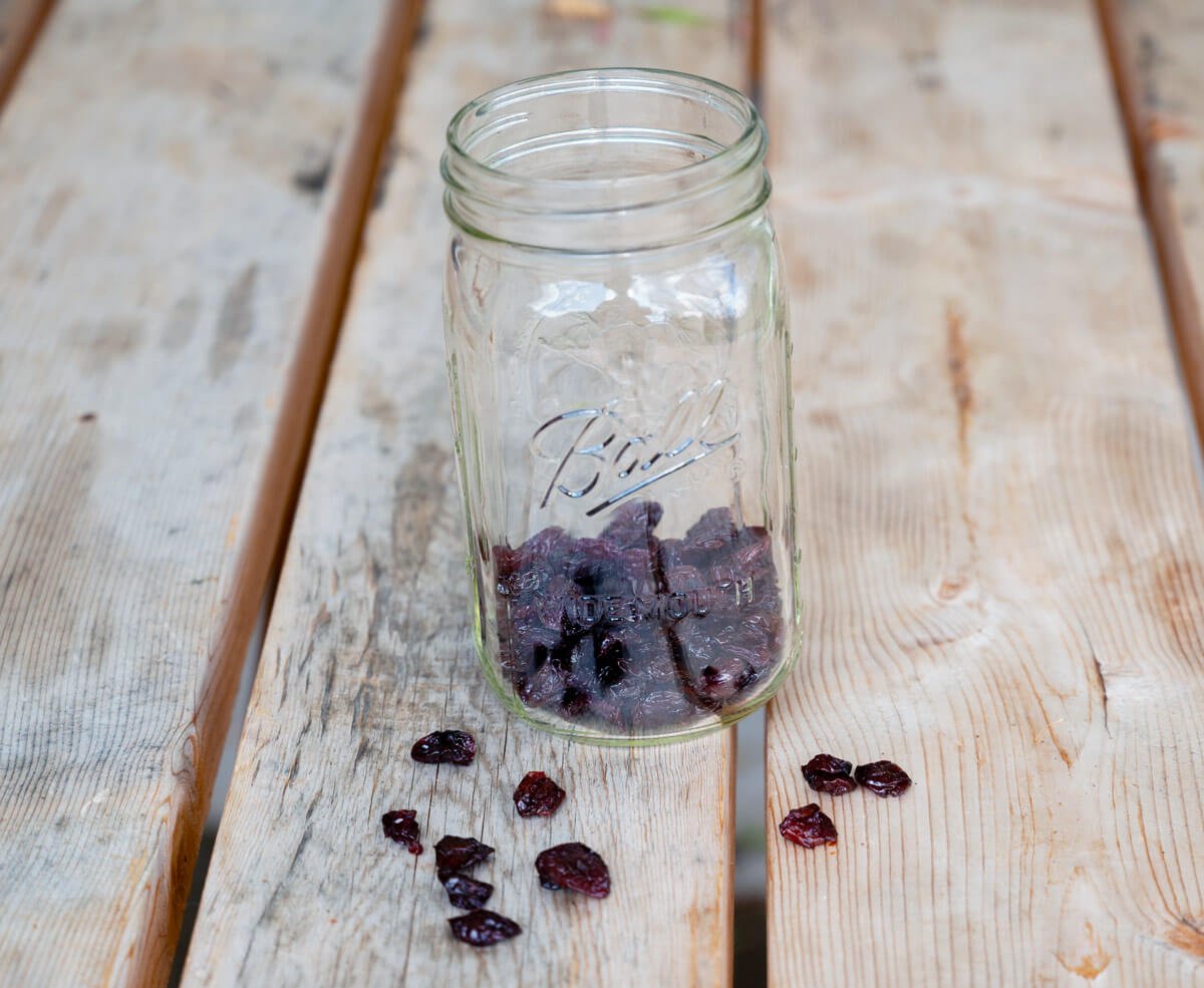 Dried cherries in the bottom of a glass Mason jar.