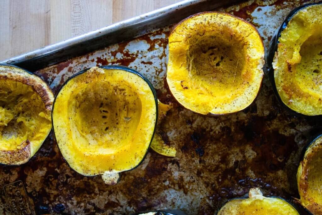 Baked acorn squash on a baking sheet.