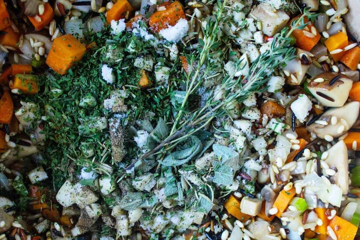 Stuffed acorn squash filling garnished with sprigs of fresh herbs.