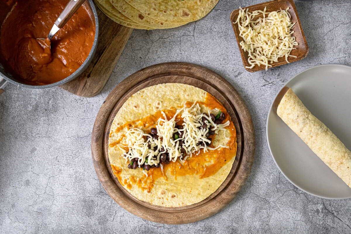 Black bean enchilada being assembled in a corn tortilla.