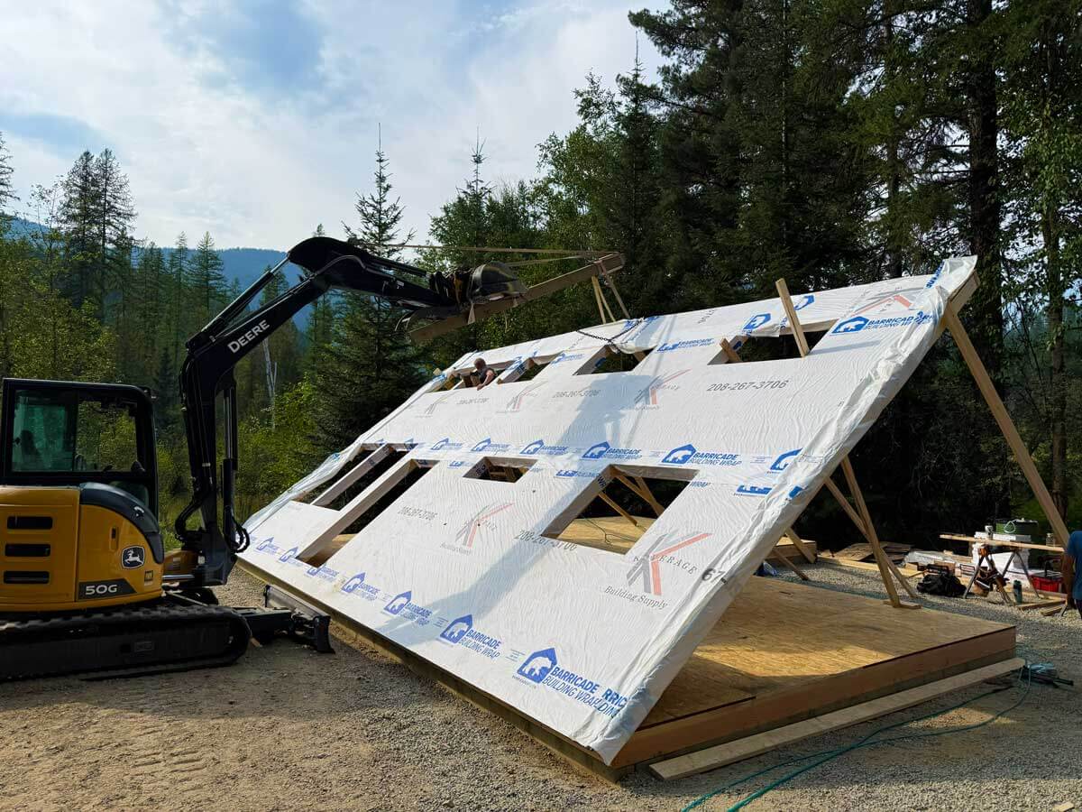 A wall of a cabin being lifted into place.