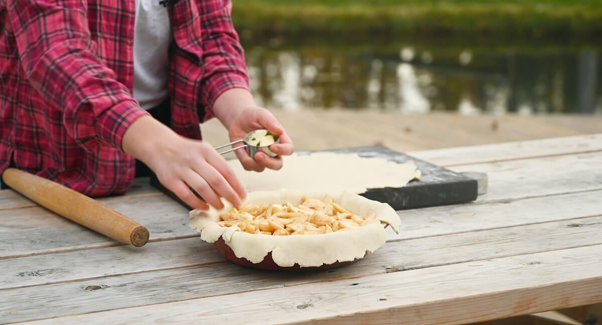 Dots of butter being added to the filling of an apple pie.