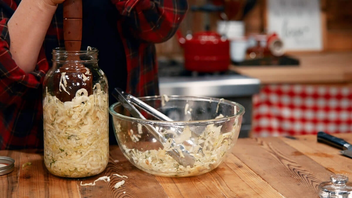 Garlic dill sauerkraut being pounded into a jar.