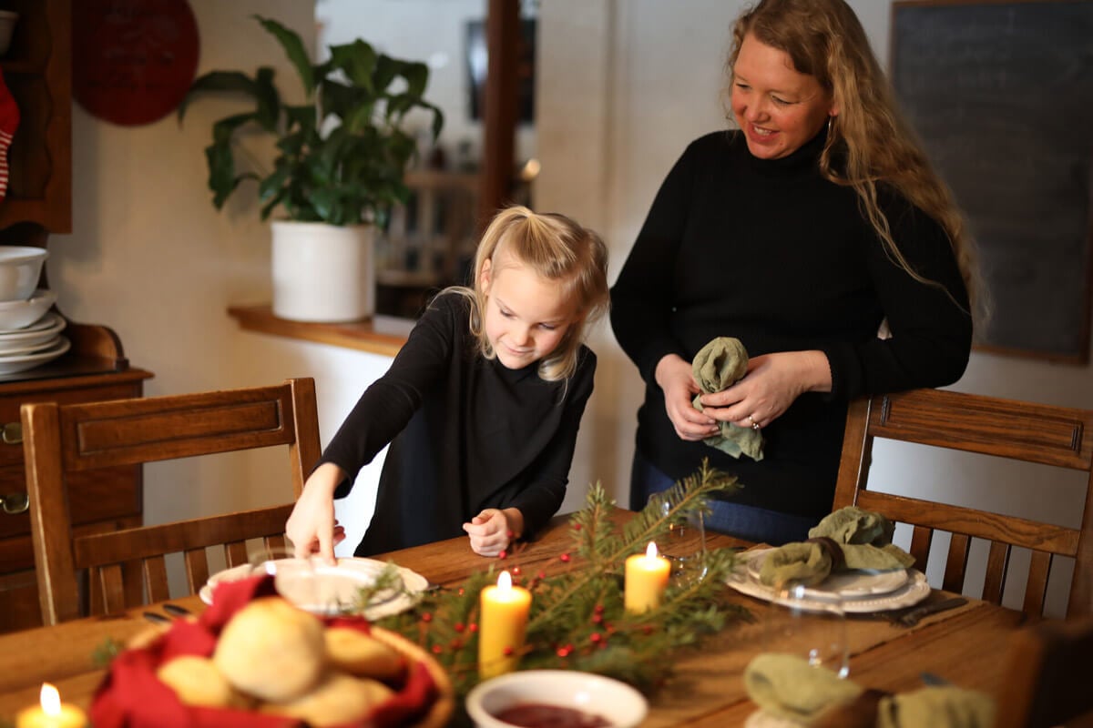 A mother watching her daughter set the holiday dinner table.