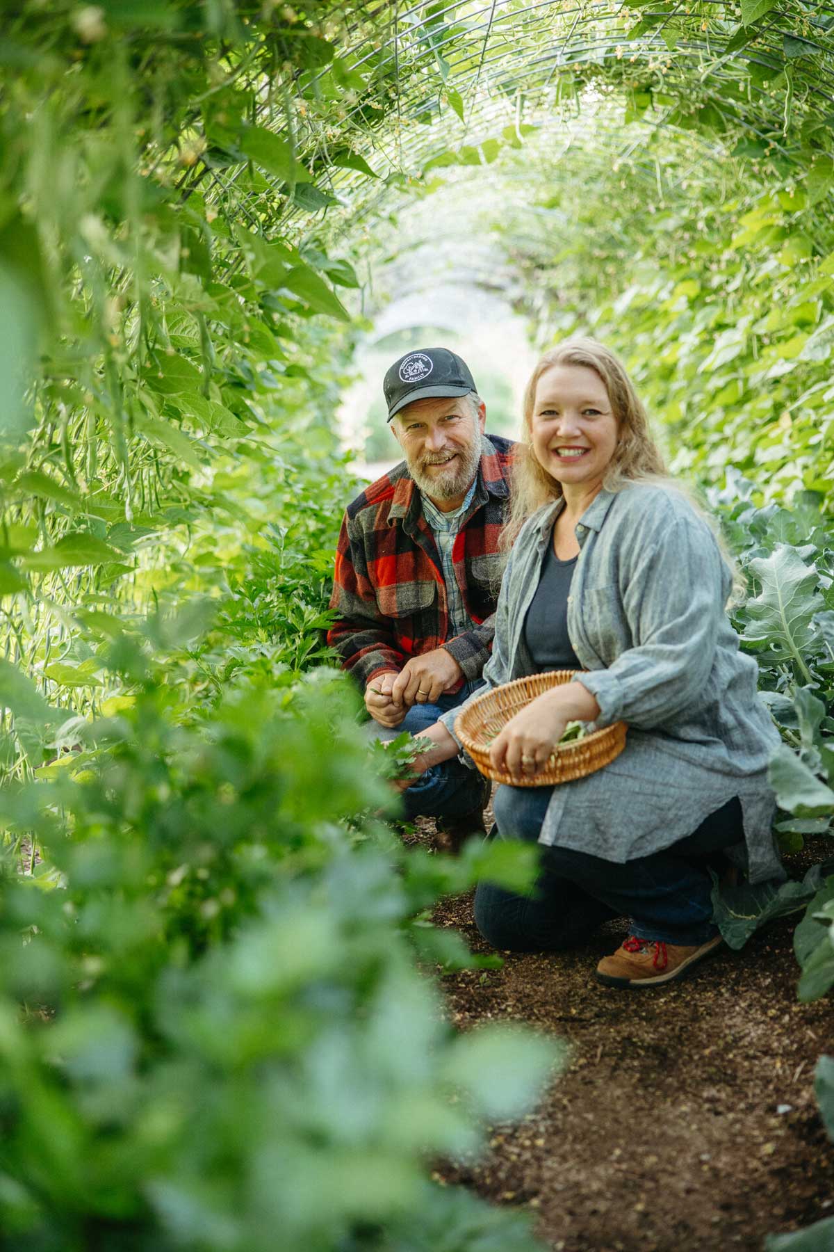 A man and woman kneeling in a garden.