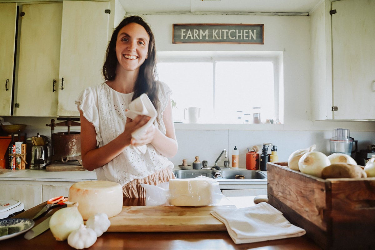 A woman in the kitchen with homemade cheeses.