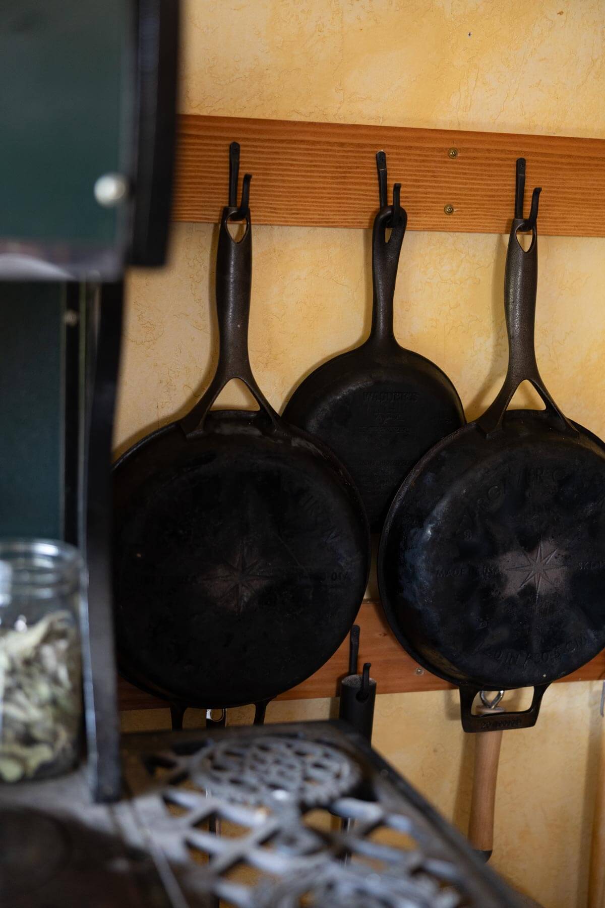 Cast iron pans hanging on wall hooks.