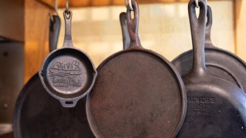 Cast iron pans hanging from a ceiling rack.
