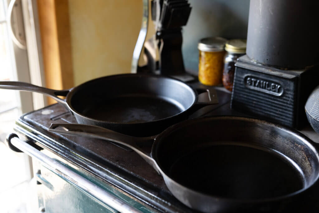 Two cast iron pans sitting on top of a wood cookstove.