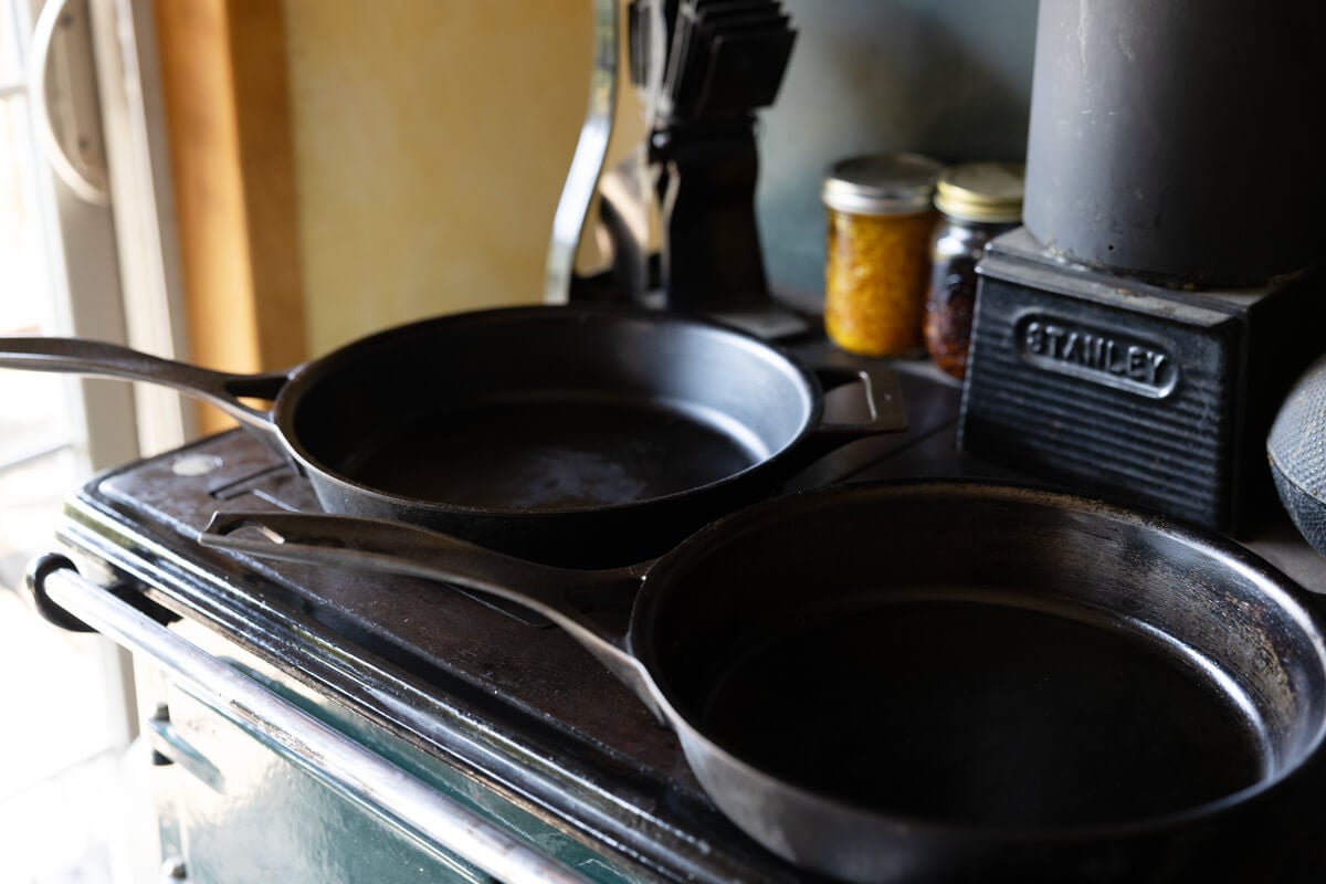 Two cast iron pans sitting on top of a wood cookstove.