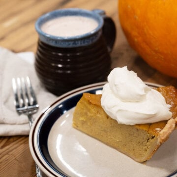 A slice of homemade pumpkin pie topped with whipped cream.