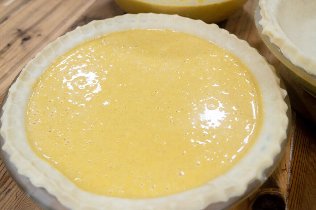 Pumpkin pie filling in a pie crust ready to bake.