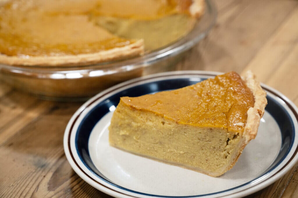 A slice of pumpkin pie on a white plate.